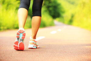 A photo of a young woman's legs showing working clothes and sneakers as she walks down a road.