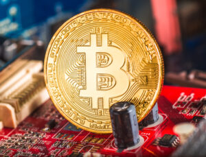 An image showing a golden Bitcoin piece on a computer circuit board.