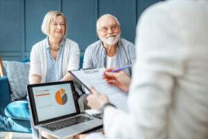 A photo showing a happy senior couple meeting with their financial advisor in their home.