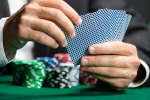 A photo showing a man’s hands holding his poker cards with many poker chips in front of him.