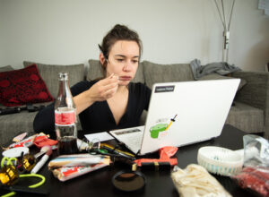 A photo of a woman working from home with an array of snacks on a messy table.