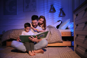 A photo showing a young father reading a bedtime story to his son and daughter.