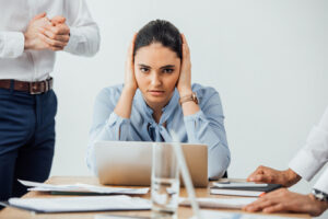 A photo showing a young woman covering her ears during a business meeting.