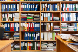 A photo of a crammed archive room stuffed with books and stacks of research papers.