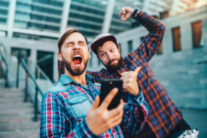 A photo of two friends showing extreme excitement while looking at one friend’s mobile phone.