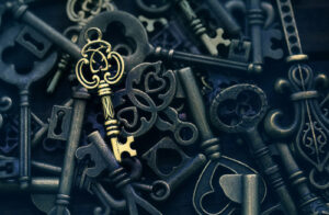 A photo showing one golden antique key atop a pile of black keys.