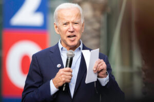 A photo of Joe Biden speaking through a microphone at a campaign event in Los Angeles, California.