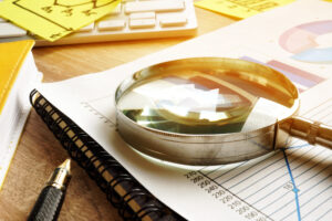 A photo showing a magnifying glass resting on top of financial reports.