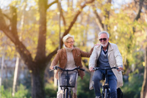 A photo showing an active senior couple riding bikes together in a park.