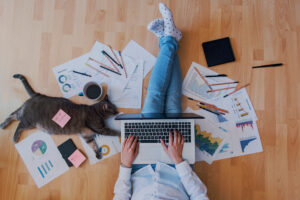 A photo showing an employee working from home, sitting on the floor with a laptop and surrounded by work documents.