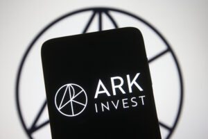 A photo illustration of the Ark Invest LLC logo on a black iPhone screen