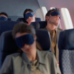 A photo of four passengers asleep on a plane.