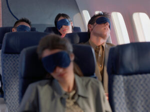 A photo of four passengers asleep on a plane.