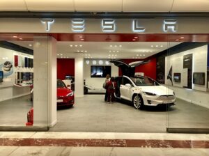 A photo of a Model S and Roadster on display in the front of a Tesla showroom