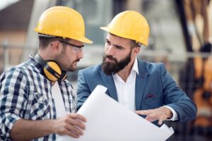 A photo of a project manager discussing the blueprint for a new building with one of his engineers.