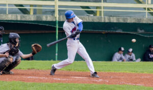 A photo of a baseball player in a white uniform mid-swing.