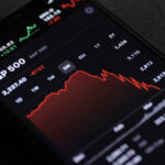 A photo of an iPhone with a chart of the S&P 500 on the screen depicting a major dip