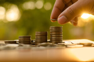 A close-up photo of a hand stacking coins in small piles