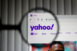 A photo of Yahoo’s logo on the homepage of a computer screen seen through a magnifying glass