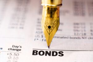 A photo of the tip of a gold calligraphy pen pointing to the word “BONDS” in a bold, black font.