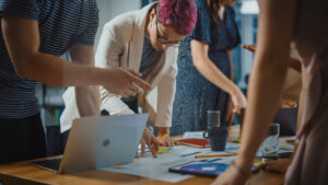 A photo of a creative team gathered around a table full of papers