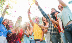 A photo of a group of friends huddled together and popping confetti cannons.