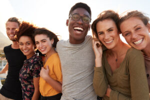 A photo of a group of six friends, arm in arm and smiling.