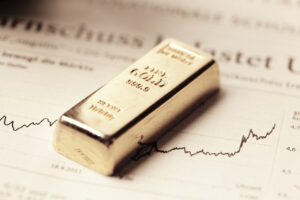 A photo of a bar of gold resting on top of a printed stock chart.