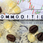 The word “commodities” is spelled out in letter cubes surrounded by coffee beans, corn and rice on top of a candlestick chart.