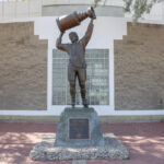 A photo of the Wayne Gretzky statue in Edmonton, Canada. Gretzky is depicted carrying a large trophy above his head.