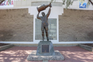 A photo of the Wayne Gretzky statue in Edmonton, Canada. Gretzky is depicted carrying a large trophy above his head.