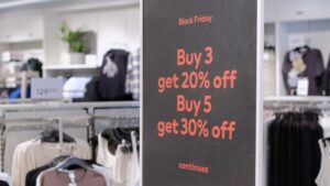 A seasonal promotional sign in a clothing store on Black Friday that reads “Buy 3 get 20% off” and “Buy 5 get 30% off.”