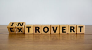 A line of lettered blocks on a wooden table spells extrovert and introvert.