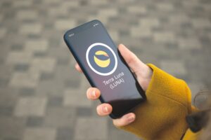 Close up of a hand holding an I-Phone with the Terra Luna cryptocurrency logo on the screen