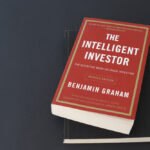 Benjamin Graham’s book The Intelligent Investor on top of a black table.