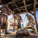A photo of the bronze statue of trade merchants weighing their payment on a scale located in Minsk, Belarus.