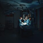 Doctors in uniform performing surgery in a low-lit operating room.
