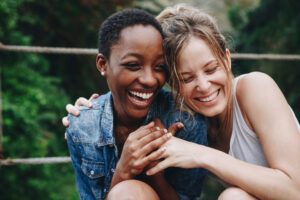 Two friends sitting down laughing together.