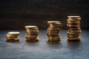 Gold coins in stacks on a dark table and each stack increases in height.