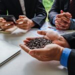 Businessman holds a handful of coffee beans while discussing investments.