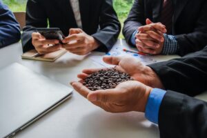 Businessman holds a handful of coffee beans while discussing investments.