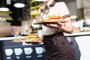 A waitress holding two trays of food at work.