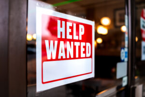 A red “Help Wanted” sign hanging on a door.