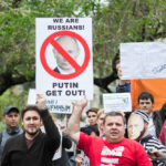 Protestors holding a sign that reads “We are Russians! Putin, get out!”