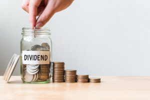 A man placing coins in a jar that reads “dividends.”