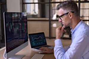 Businessman in front of a computer reviewing stock charts