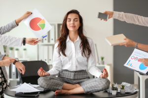 A woman meditating on a desk with a series of problems around her.