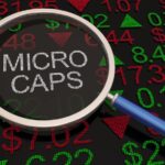 The word “MICROCAPS” shown through a magnifying glass with numbers and data around it.