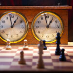 Two wooden vintage chess clocks with an endgame on the chessboard.