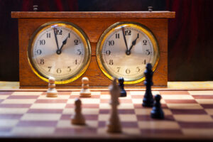 Two wooden vintage chess clocks with an endgame on the chessboard.